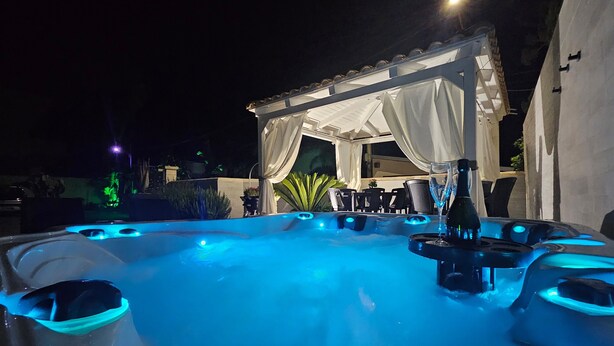 Ein Whirlpoolbereich mit überdachter Sitzgelegenheit und einer Champagnerflasche.