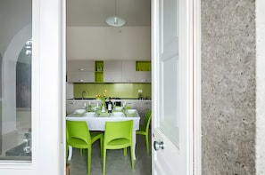 Een moderne keuken met witte kastjes, een eettafel met groene stoelen en een zichtbaar raam.