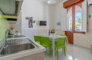 Une cuisine moderne équipée d’un évier, d’une table à manger avec des chaises, et offrant une vue sur l’extérieur grâce à une porte.
