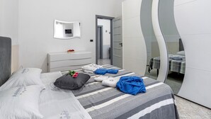 Ein modernes Hotelzimmer mit einem Bett, einem Nachttisch, einem Spiegel und einem Schrank mit geschwungener Form.