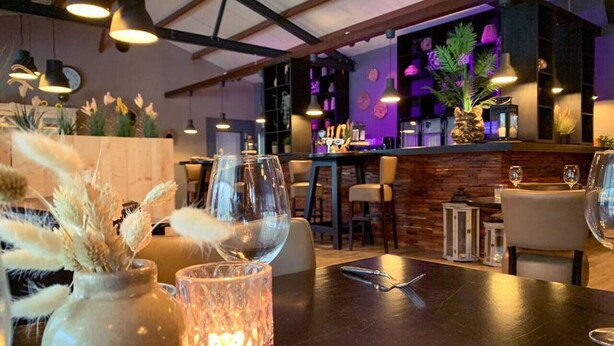 A restaurant with a wooden table set for two, featuring a vase with dried wheat and a candle. - Chatel Studio voor 2 personen | Resort de Heimolen (Baarle-Nassau)