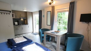 A compact hotel room with two beds, a kitchenette, a dining area, and a TV. - Chatel Studio voor 2 personen | Resort de Heimolen (Baarle-Nassau)