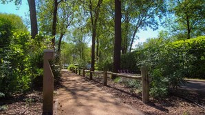 A dirt path flanked by wooden fences and lush greenery, leading to a parking area. - Chatel Studio voor 2 personen | Resort de Heimolen (Baarle-Nassau)