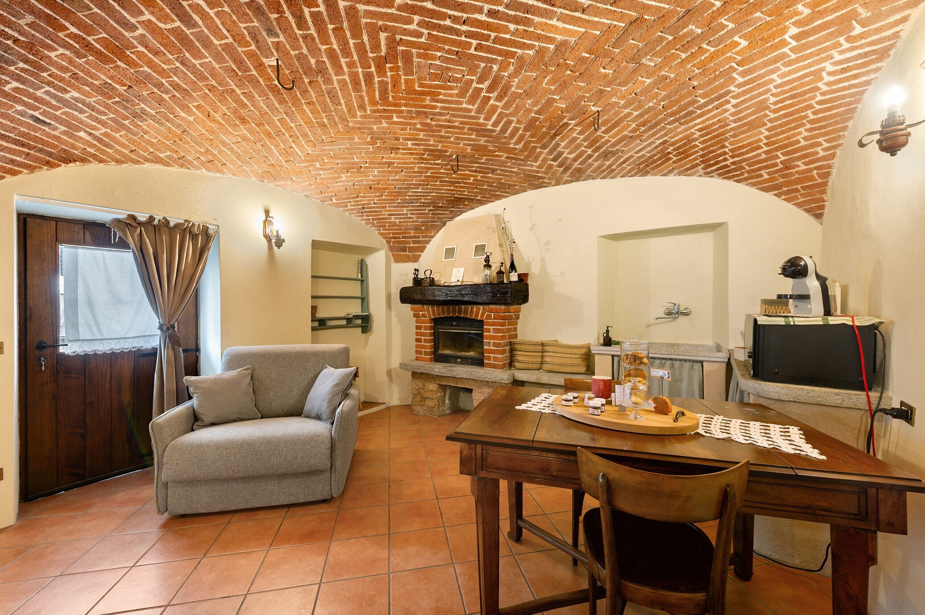 A cozy living area with a brick ceiling, a fireplace, a sofa, and a dining table.