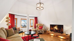 Ein modernes Wohnzimmer mit Sofa, Sessel, Fernseher und Kamin.