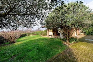 A brick building with a small garden and a tree in front.