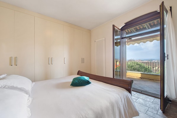 A bedroom with a bed, a window, and a view of the outside.