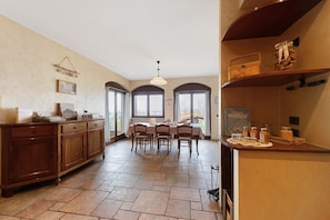 A kitchen with a dining table, wooden cabinets, and a view through the windows.
