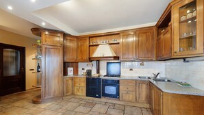 Eine Küche mit Holzausstattung, einem Herd, Backofen und einer gefliesten Spritzschutzwand.