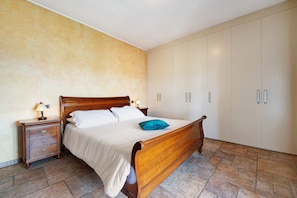 A bedroom with a wooden bed, a nightstand, a lamp, and a wardrobe.