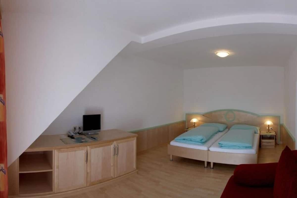 Quarto com cama, mesas de cabeceira, escrivaninha e guarda-roupa.