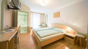 A bedroom with a bed, desk, chair, and a small stool. - Hotel zum Kirchenwirt Mariazell (Mariazell)