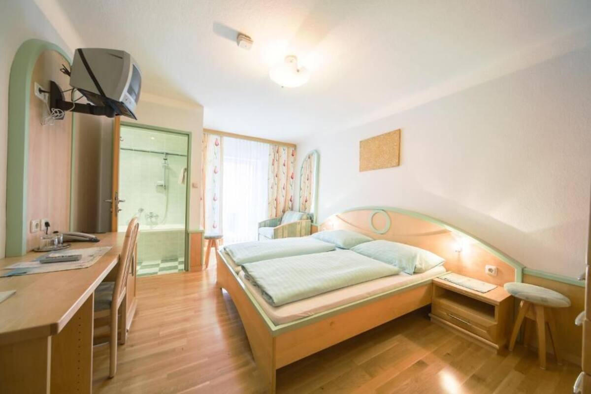 Quarto com cama, escrivaninha, cadeira e um banquinho.
