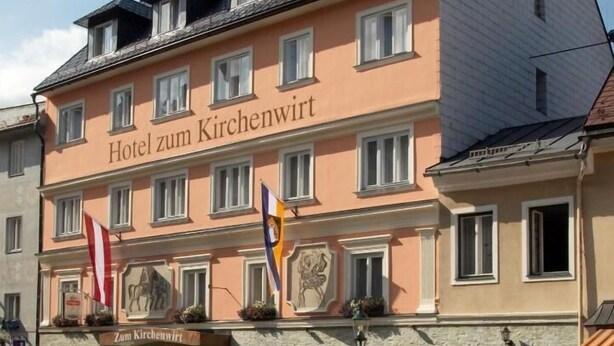 Un bâtiment d’hôtel appelé « Hotel zum Kirchenwirt », de style architectural classique, avec de nombreuses fenêtres et une façade en pierre.