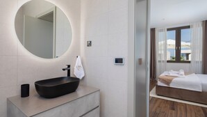 A modern bathroom with a round mirror, a black vessel sink, and a towel hanging on the wall. - The Palms Resort 2BR Villa Dream Four with Pool (Tkon)