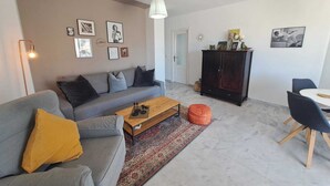 A modern living room with a grey sofa, a wooden coffee table, a dark cabinet, and a dining area with a white table and chairs. - New!! Enjoy Benalmadena Costa!! Magnificent views, 2 bedrooms, terrace, garage (Benalmádena)