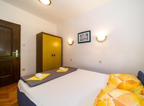 A bedroom with a bed, a wardrobe, and two wall-mounted lights.