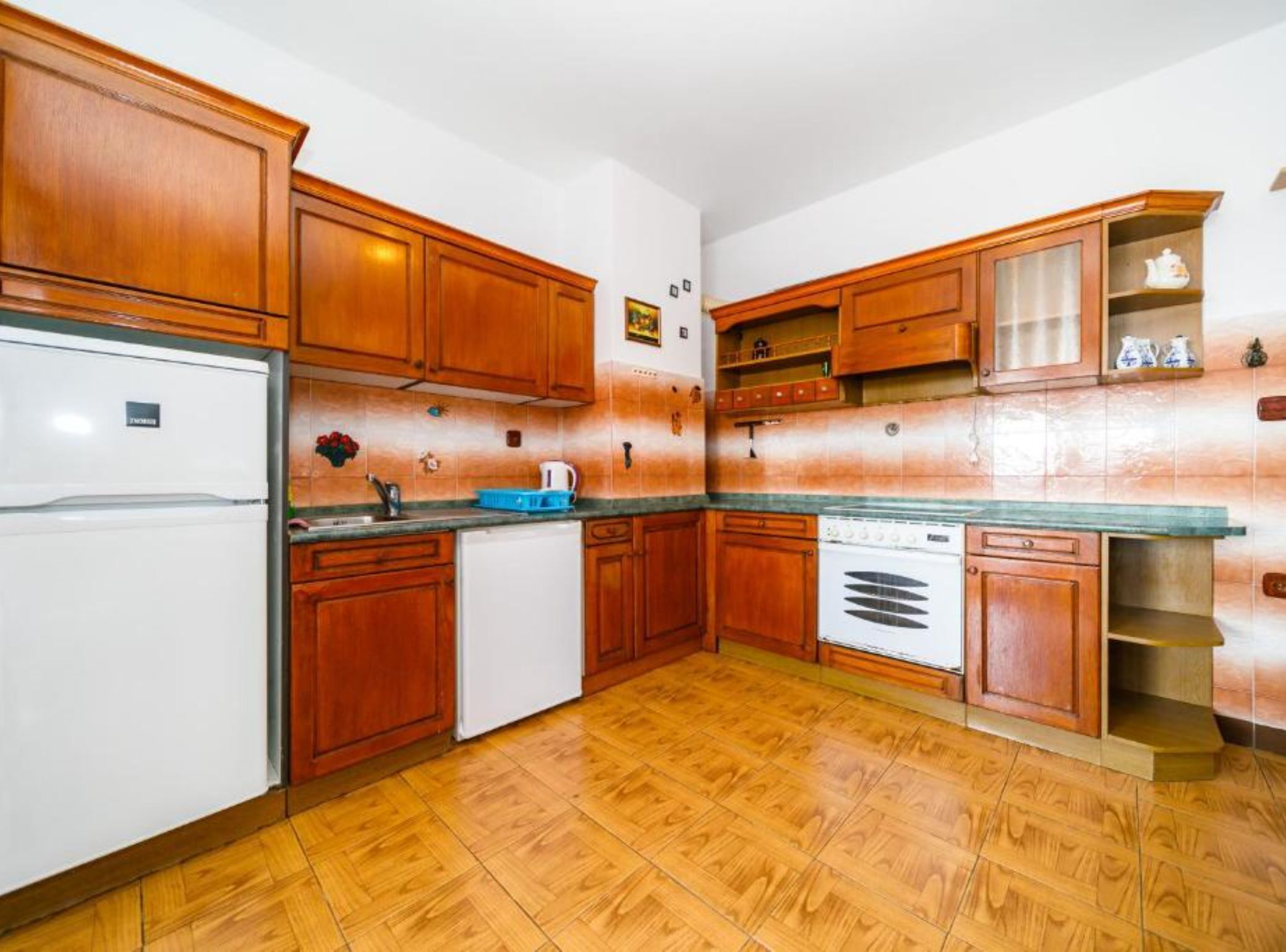 A kitchen with wooden cabinets, a refrigerator, a stove, and a sink.