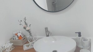 A bathroom with a round mirror, a white sink, and a wooden countertop. - Room-serene Apartment Escape in Achada F (Santa Cruz)