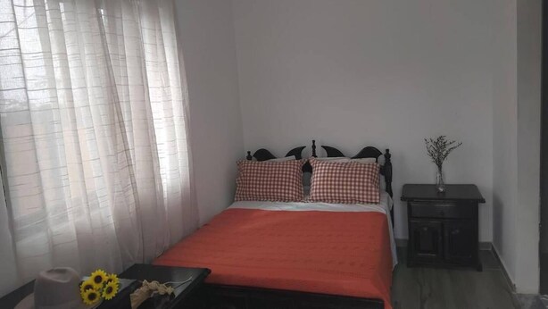 A bedroom with a bed, a nightstand, and a window with sheer curtains. - Room-serene Apartment Escape in Achada F (Santa Cruz)