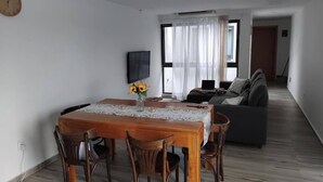 Ein Essbereich mit einem Holztisch, Stühlen, einer Vase mit Blumen und einer Uhr an der Wand.