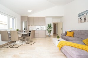 A modern apartment with a dining area, kitchen, and living room. - Two-bedroom apartment Pulse with poolside patio and sea view (Novalja)