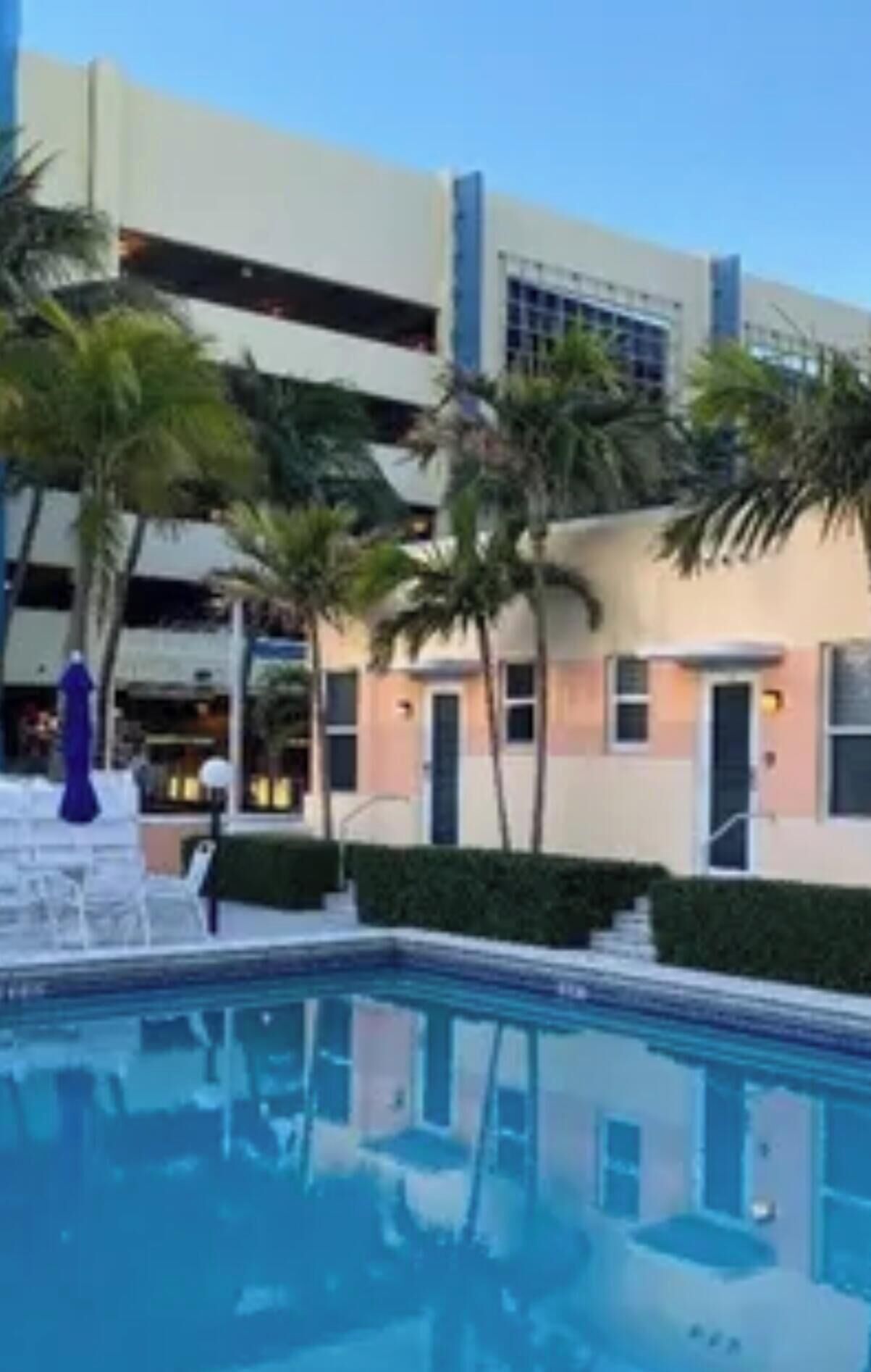 A swimming pool with a reflection of a building and palm trees.