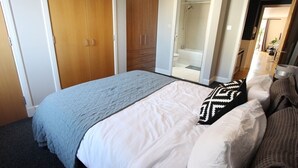 A bedroom with a bed, a wardrobe, and a bathroom visible through an open door.