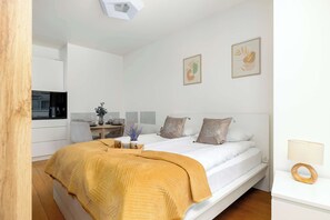 Quarto moderno com cama, mesa de cabeceira e espaço de trabalho.