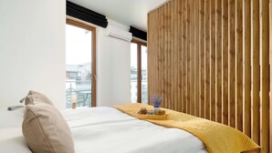 Ein modernes Hotelzimmer mit einem großen Bett, einer Wand aus Holzpaneelen und Blick auf die Stadt.