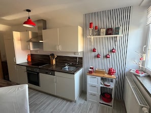Eine moderne Küche mit schwarzem Arbeitsplatz, Edelstahlgeräten und einer gestreiften Wand mit roten Tassen.