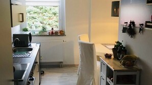 Ett kompakt kök med ett fönster, en diskho, en spis och en liten matplats.