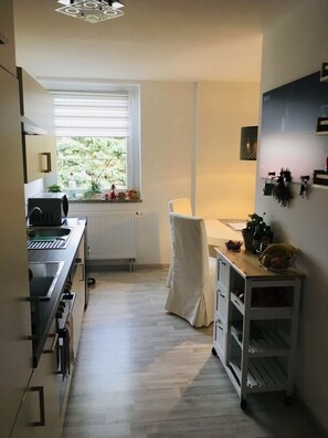 Eine kleine Küche mit Fenster, Spüle, Herd und einer Essgelegenheit.