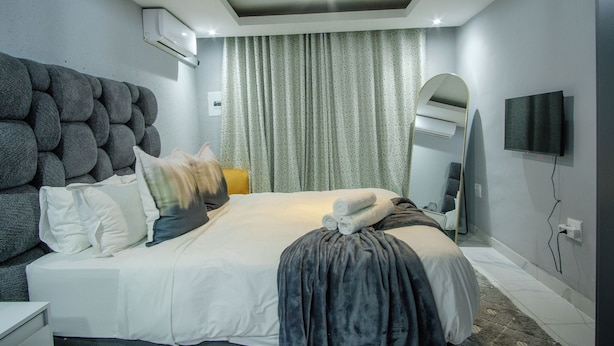Ett modernt hotellrum med en stor säng, en platt-TV, en taklampa och en luftkonditioneringsanläggning.
