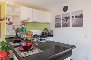 A kitchen with a central island, white cabinets, and a clock on the wall. - Eco Paradise #101 - Apt in Cumbuco by Carpediem (Caucaia)