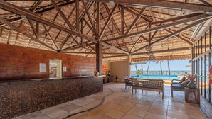 A reception area with a wooden counter, tiled floor, and a pool view. - Eco Paradise #101 - Apt in Cumbuco by Carpediem (Caucaia)