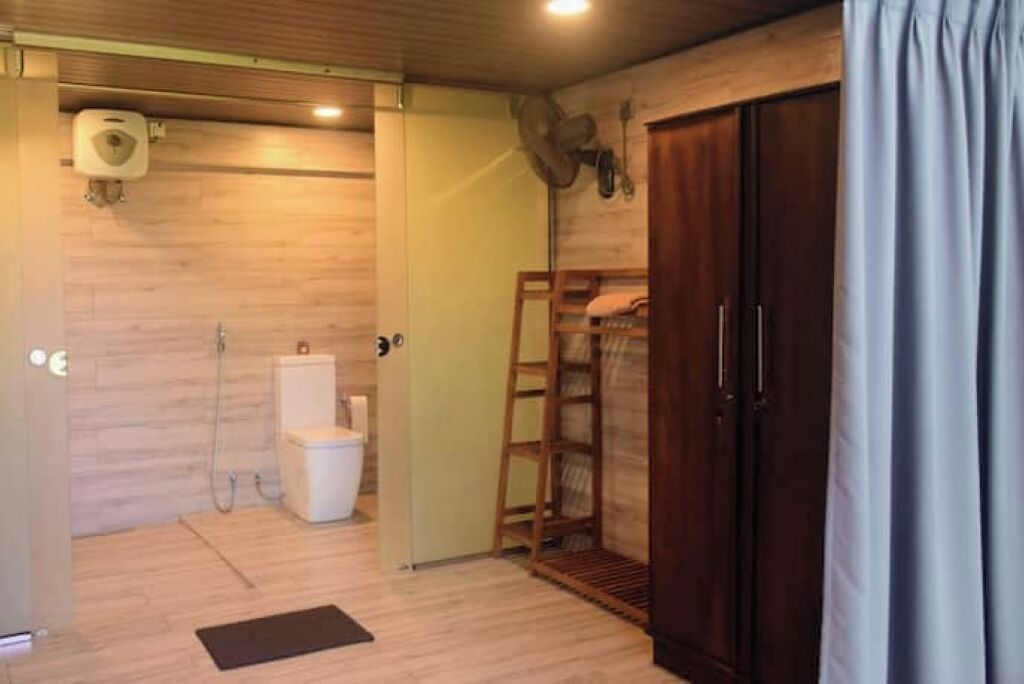 A bathroom with a toilet, shower, and a wooden ladder shelf.