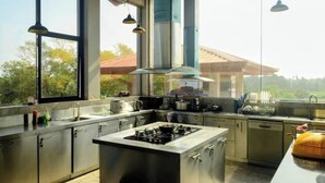 A modern kitchen with stainless steel appliances, large windows, and pendant lighting.