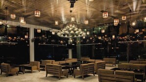 A spacious indoor area with multiple seating arrangements, a large chandelier, and large windows offering views.