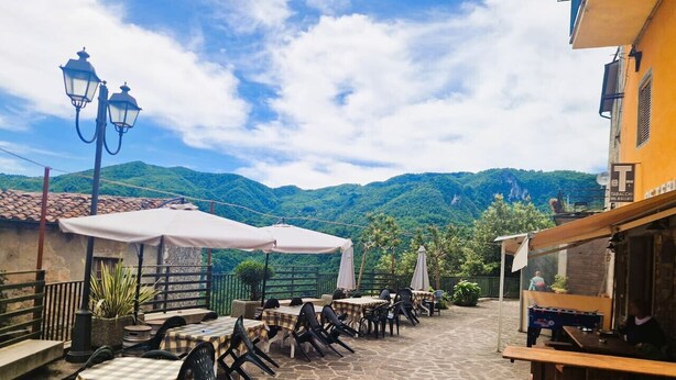 An outdoor patio with tables and chairs, a foosball table, and a view of green hills. - Authentic Tuscany Stay with Epic Views & Space for All (Cardoso)