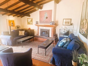 Un salon chaleureux avec une cheminée, deux canapés, une table basse et un tapis à motifs.
