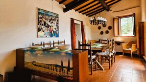 A dining area with a long wooden table, chairs, a chandelier, and a painting of a landscape. - Authentic Tuscany Stay with Epic Views & Space for All (Cardoso)