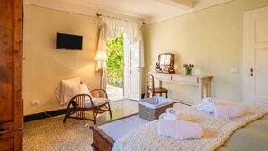 Une chambre à coucher avec un lit, une chaise, un bureau, une télévision et une fenêtre avec des rideaux.