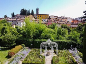 A garden with a white gazebo, surrounded by lush greenery and a pathway. In the background, there is a town with colorful buildings and a tower. - * Villa Fiorentina - Private Oasis in Barga Town (Barga)