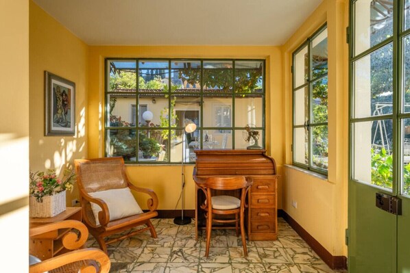 A room with a large window, a desk, a chair, and a small table with a basket. - * Villa Fiorentina - Private Oasis in Barga Town (Barga)