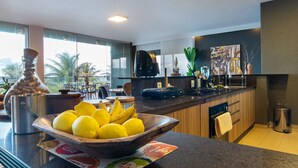 A modern kitchen with a large window, a bowl of lemons and bananas, a coffee maker, and a sink. - Luxo a Beira Mar - Mansao Exclusiva por Carpediem (Extremoz)
