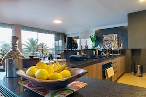 A modern kitchen with a large window, a bowl of lemons and bananas, a coffee maker, and a sink.
