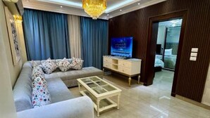 A living room with a sofa, a coffee table, a TV, and a dresser. - Royal Gameat Al Dewal Residence (Giza Governorate)
