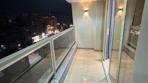 A balcony with a glass railing, a tiled floor, and a city view at night. - Royal Gameat Al Dewal Residence (Giza Governorate)