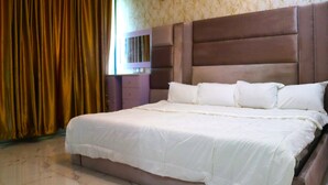 Un dormitorio con una cama grande, cabecera y ventana con cortinas.
